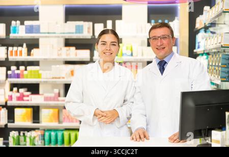 Zwei lächelnde weibliche und männliche Apotheker stehen Schulter an Schulter in der apotheke Stockfoto