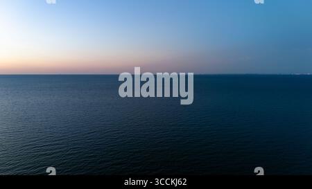 Ruhiger Ozean Horizont in der Abenddämmerung mit sanften pastellfarbenen Himmelsreflexen. Stockfoto