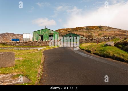 Ein grünes Gebäude mit weißem Dach befindet sich an einer Straße. Die Straße ist leer und der Himmel ist blau Stockfoto