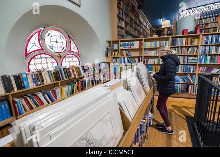 Eine junge Frau, die sich Vintage-Drucke und Karten in Leakey's Bookshop, Church Street, Inverness, Highland, Schottland anschaut. Vereinigtes Königreich Stockfoto