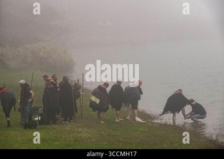 30. März 2023, Furnas, Azoren, Portugal: Ein römisch-katholischer Priester wäscht die Füße von Pilgern, die als Romeiros bekannt sind, an einem nebeligen Tag am Ufer des Furnassees, 30. März 2023 in Lagoa das FurnÃ, Portugal. Die Pilger besuchen 100 Schreine und Kirchen während ihrer 8-tägigen Wanderung um die Azoren-Insel Sao Miguel, die aus dem Jahr 1522 stammt, als ein Erdbeben die ersten Siedlungen zerstörte. (Bild: © Richard Ellis/ZUMA Press Wire) Stockfoto