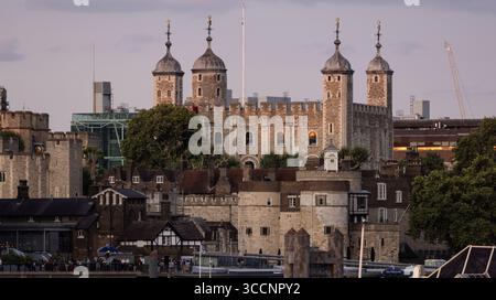 Blick auf den Tower of London bei Sonnenuntergang mit abgesenkter Flagge, der die historischen Steinmauern und Türme vor einem bewölkten Himmel in London, Großbritannien, zeigt Stockfoto