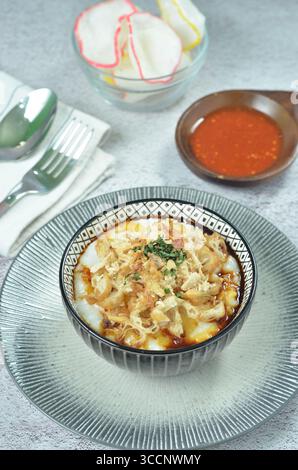 Reisbrei serviert mit geriebenem Chähnchen, Cakwe, Crackern und Chili Stockfoto