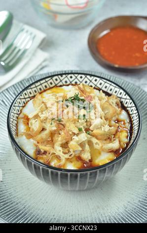 Reisbrei serviert mit geriebenem Chähnchen, Cakwe, Crackern und Chili Stockfoto