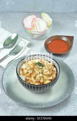 Reisbrei serviert mit geriebenem Chähnchen, Cakwe, Crackern und Chili Stockfoto