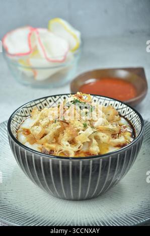 Reisbrei serviert mit geriebenem Chähnchen, Cakwe, Crackern und Chili Stockfoto