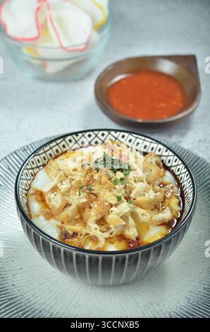 Reisbrei serviert mit geriebenem Chähnchen, Cakwe, Crackern und Chili Stockfoto