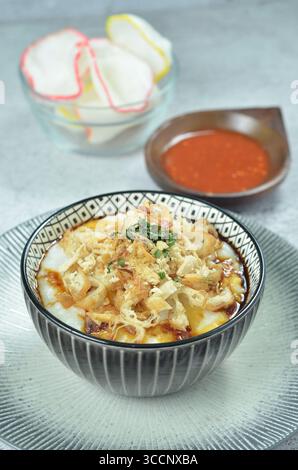 Reisbrei serviert mit geriebenem Chähnchen, Cakwe, Crackern und Chili Stockfoto