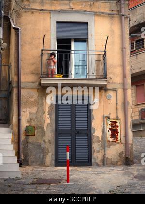 Kind auf Balkon eines alten Wohngebäudes mit verwitterten Wänden in Enna Sizilien Italien Stockfoto