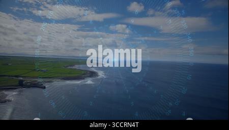 Die digitale HUD-Kompassanzeige schwebt über Küstenklippen, trifft auf Felder und den Ozean dahinter Stockfoto