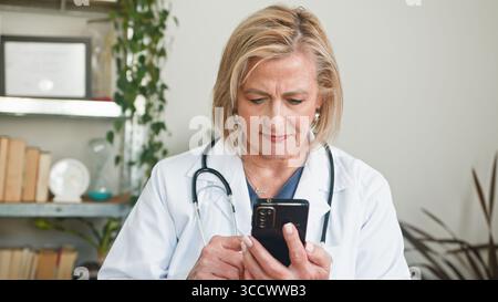 Professionelle Oberärztin mit Smartphone in ihrer Arztpraxis Stockfoto