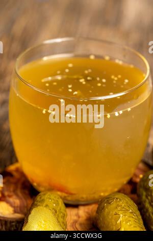 Gurkenmarinade im Glas mit Gewürzen und eingelegten knusprigen Gurken auf dem Tisch, Gurken in Wasser auf dem Tisch Stockfoto