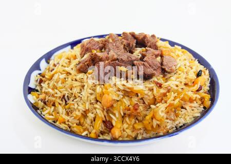 Usbekische Pilaw mit zartem Rindfleisch, Reis, Kichererbsen und Karotten, serviert auf einer traditionellen blauen Keramikplatte Stockfoto