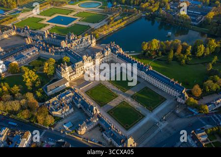 Aus der Vogelperspektive der kunstvollen Architektur und der strukturierten Gärten von Château de Fontainebleau treffen auf den ruhigen See, eine Symphonie aus Stein, Wasser und Grün, Fontainebleau, Île-de-France, Frankreich. Stockfoto