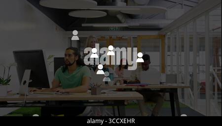 Arbeitender Mann mit grünem T-Stück, der am Computer im Großraumbüro schreibt, mit Kaffeetassen, Kopierraum Stockfoto