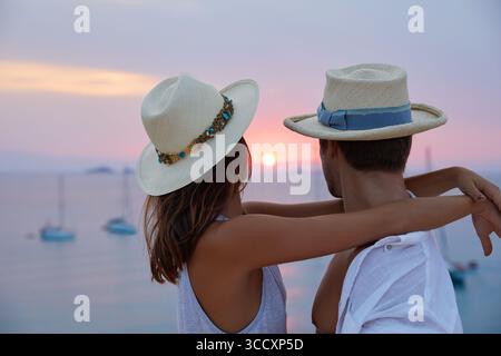 Ein Paar, das den Sonnenuntergang ansieht und Hüte trägt Stockfoto