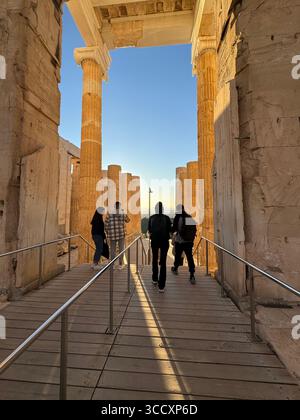 Goldene Stunde Sonnenuntergang am Eingang des Akropolis-Komplexes (Acrópole Propileia) in Athen, Griechenland, mit Touristen, die die Treppe hinunter laufen. Stockfoto
