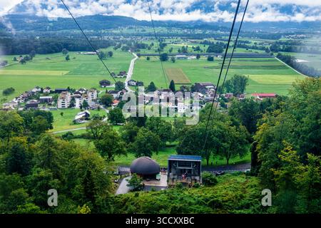 Blick von der Seilbahn, die im Sommer in der Schweiz mit Seilbahn über den grünen Hügel im Vorort hinaufsteigt Stockfoto