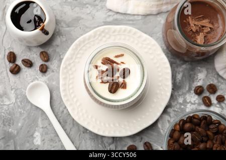 Köstliche Panna Cotta mit Schokoladenbrocken und Kaffeebohnen serviert auf grauem, strukturiertem Tisch, flach gelegen Stockfoto