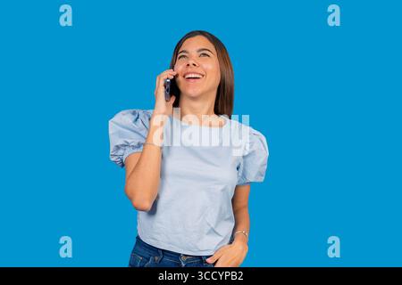 Fröhliche junge Frau, die ein angenehmes Telefongespräch führt und Freude und Positivität ausdrückt Stockfoto