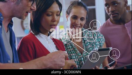 Zusammenarbeit mit vier Kollegen, die Netzwerkdiagramme im Büro auf einem Tablet mit Smartphone-Symbolen anzeigen Stockfoto