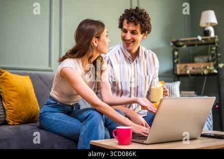 Ein erwachsenes Paar sitzt zu Hause auf dem Sofa und benutzt einen Laptop. Stockfoto