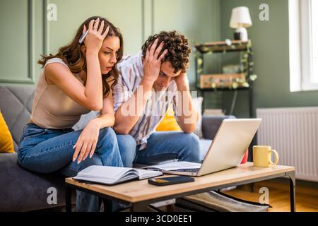 Ein Paar überprüft die Hausfinanzierung auf dem Laptop. Sie sind schockiert wegen des schlechten Familienbudgets. Stockfoto
