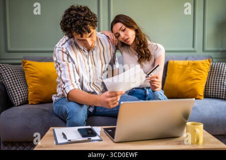 Ein paar, das über Hausfinanzen spricht, während er Rechnungen prüft. Sie überprüfen die Finanzdokumente und berechnen das Familienbudget im Wohnzimmer. Stockfoto
