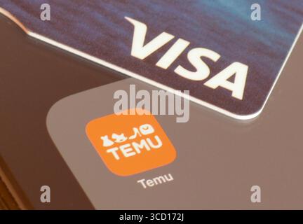 Temu Shopping-App auf einem Smartphone-Bildschirm mit einer VISA-Karte für die Zahlung Stockfoto