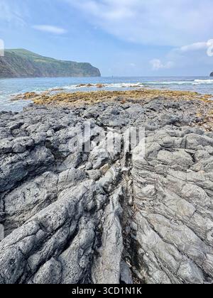 Basaltische Lavaformationen und Küstenfelsen mit Mosteiros-Inseln im Hintergrund, Insel São Miguel, Azoren. Stockfoto