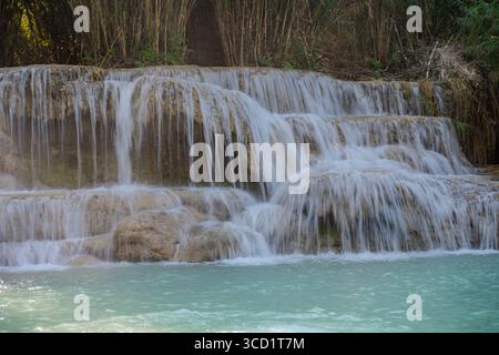Klarer türkisfarbener Pool und gestufte Kalksteinkaskaden des Kuang Si Wasserfalls im üppigen Wald in der Nähe von Luang Prabang, Laos Stockfoto