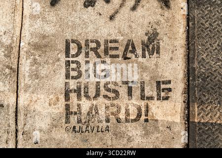 Schablonengraffiti – „Dream Big Hustle Hard“ Stockfoto