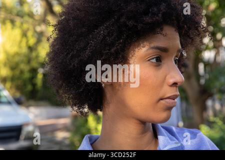 Afroamerikanerin, die an der Auffahrt steht, trägt blaues Oberteil neben weißem Van, Kopierraum Stockfoto