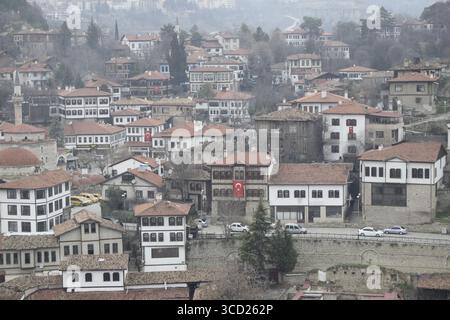 Blick auf die rot gedeckten osmanischen Häuser kaskadieren die sanften Hänge hinunter und verschmelzen mit den gedämpften Grünflächen der umliegenden Hügel, Safranbolu, Karabük, Türkiye. Stockfoto