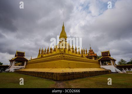 Weitwinkelblick auf Pha That Luang in Vientiane, Laos – legendäre goldene buddhistische Stupa und heiliges Denkmal an einem bewölkten Tag Stockfoto
