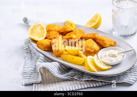 Traditioneller Fisch und Chips mit Zitronen- und Tatarensauce auf Servierteller Stockfoto