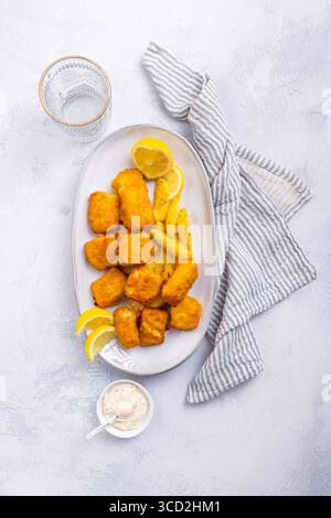Traditioneller Fisch und Chips mit Zitronen- und Tatarensauce auf Servierteller Stockfoto