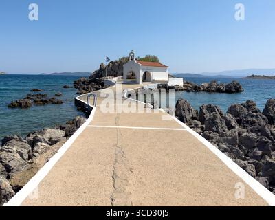 Agios Isidoros kleine Kirche, Insel Chios, Griechenland. Traditionelle Architekturkapelle auf einer felsigen Insel, die durch einen schmalen Betonwalkw mit dem Ufer verbunden ist Stockfoto