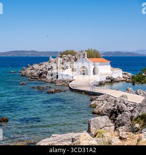 Chios, Agios Isidoros kleine Kirche, Griechenland. Traditionelle Architekturkapelle mit rotem Ziegeldach und Glockenturm auf Felsen, sonniger Sommertag Stockfoto