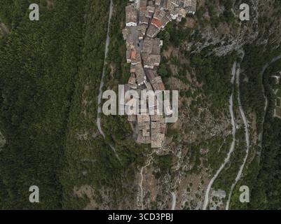 Blick aus der Vogelperspektive auf das Dorf, das sich an den Berghängen anschmiegt, mit gewundenen Straßen, die sich durch das üppige Grün schlängeln, Castrovalva, Abruzzen, Italien. Stockfoto