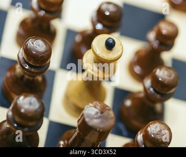 Schachfiguren stehen auf einem Schachbrett. Bauern umgaben die Königin. Angriff und Verteidigung. Selektiver Fokus Stockfoto