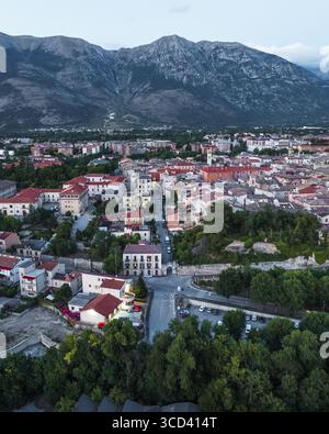 Blick aus der Vogelperspektive auf das alte Stadtbild, eingebettet unter dem wachsamen Blick der majestätischen Berge, einem Wandteppich aus Terrakotta-Dächern und grünen Bäumen, Sulmona, Abruzzen, Italien. Stockfoto