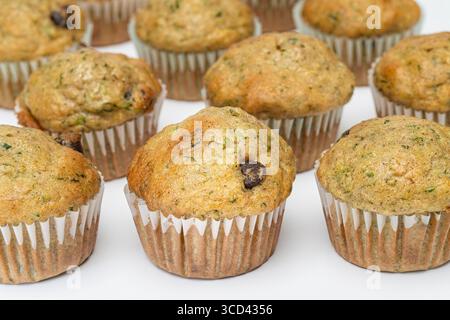 Reihen frisch gebackener Zucchini und Schokoladen-Chip-Muffins auf weißem Hintergrund Stockfoto