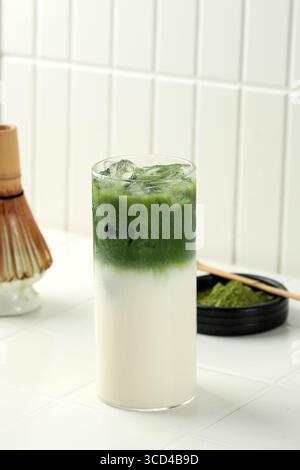 Ein Glas Eismatcha Latte, grüner Tee mit Milch und Sojamilch. Matcha-Tee mit Matcha-Puderlöffel Stockfoto