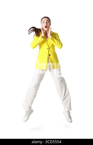Frau in gelber Jacke, die auf weißem Hintergrund springt Stockfoto