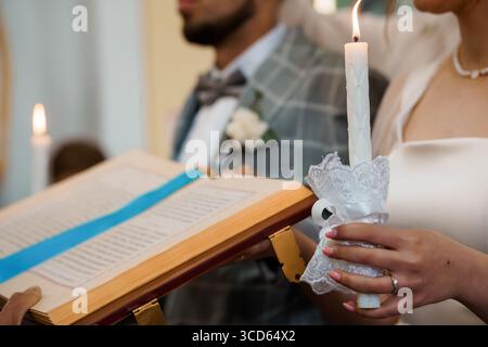 Intime Szene, in der eine Braut und ein Bräutigam während einer traditionellen Hochzeitszeremonie Kerzen zünden, die Liebe, Glauben und lebenslanges Engagement symbolisieren. Also Stockfoto