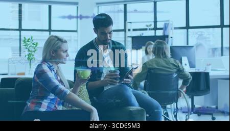 Zusammenarbeit mit Kollegen, die Inhalte auf einem Tablet in der modernen Bürolounge mit Kaffeetassen überprüfen Stockfoto