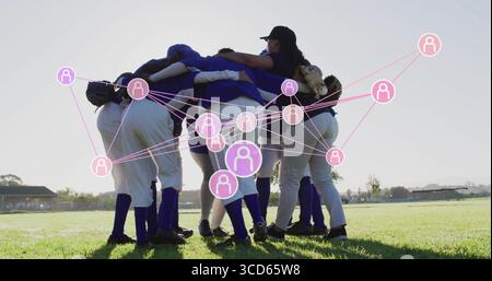 Sieben Softballspieler, die Handschuhe halten, verbinden ihre Arme auf dem Feld mit pinkem Netzwerk Stockfoto