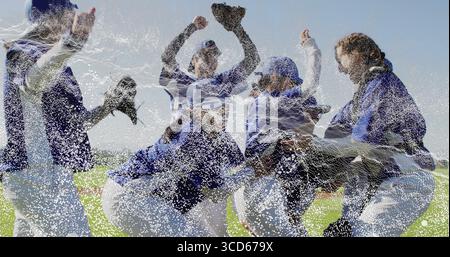 Softballspieler, die ihre Arme auf dem Außenfeld heben, mit Trikots-Kappen-Stollen und Handschuhen Stockfoto