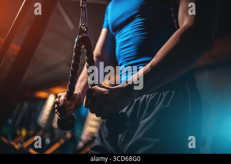 Closeup männlicher Bodybuilder, der Trizeps mit Seil im Fitnessstudio drückt, Cropped Shot man trainiert die Armmuskeln auf der Seilmaschine während des Workouts Stockfoto